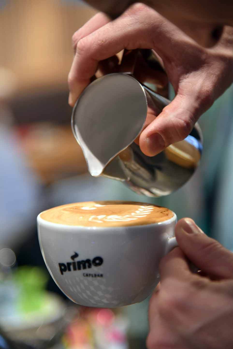 Durch Latte Art wird beim Eingießen der Milch in die Cappuccinoe Tasse in florales Muster auf die Schaumoberfläche gezeichnet